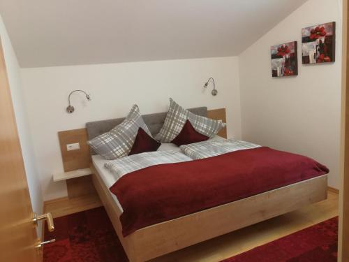 a bedroom with a bed with red blanket and pillows at Ferienwohnungen Oranhof in Velden am Wörthersee