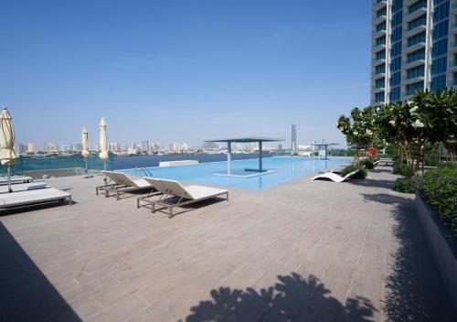 a swimming pool with lounge chairs on a building at Nasma Luxury Stays - The Grand, Dubai Creek Harbour in Dubai