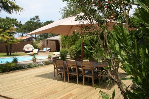 a table and chairs under an umbrella next to a pool at Chambre d'Hôtes Etchebri in Anglet