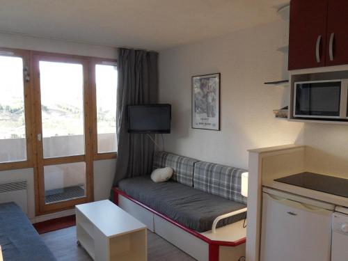 Elle comprend un petit salon doté d'un canapé et d'une télévision. dans l'établissement Appartement cosy au pied des pistes avec balcon et parking - FR-1-181-2040, à La Plagne Tarentaise