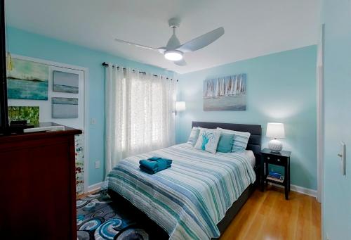 a blue bedroom with a bed and a ceiling fan at Bijou De La Beach in Hilton Head Island