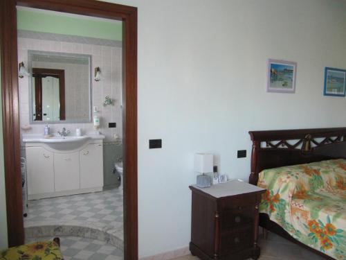 a bedroom with a bed and a bathroom with a sink at Il Portico in Uras