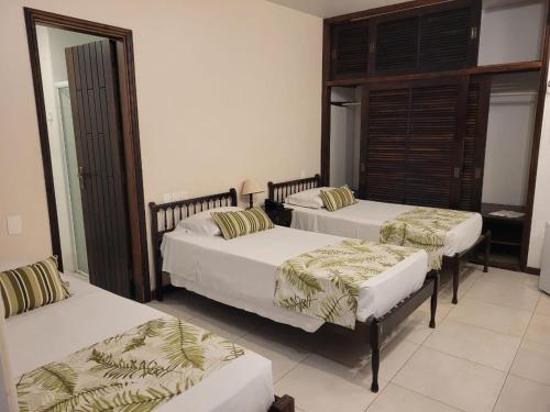 a room with three beds and two chairs in it at Ubatuba Palace Hotel in Ubatuba