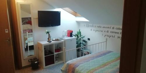 1 dormitorio con 1 cama y TV en la pared en La tua mansarda a Bergamo, en Bérgamo