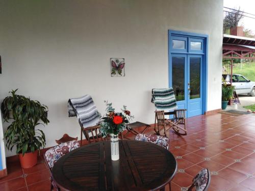 a wooden table with chairs and a vase with flowers at Casa Bartzis, Close to Orosi and Tapanti National Park in Orosí