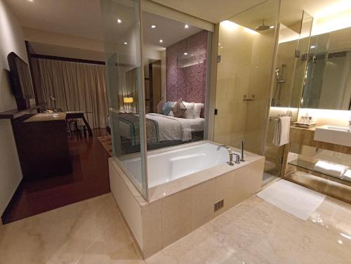 a bathroom with a tub and a bed in a room at Hotel Royal Orchid Jaipur, Tonk Road in Jaipur