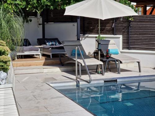 einen Pool mit 2 Stühlen und einem Sonnenschirm in der Unterkunft "sunnseit" Appartement in Söll