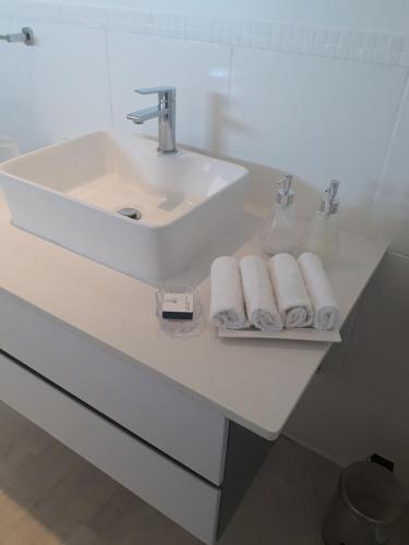 ein weißes Badezimmer mit einem Waschbecken und Handtüchern auf einem Regal in der Unterkunft 511 Umdloti Resort WOW! Amazing Breakers Views in Umdloti
