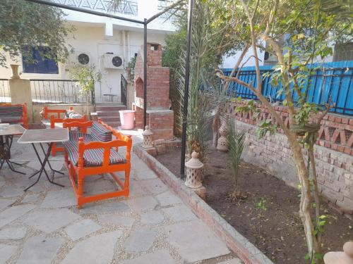 a patio with orange chairs and a table and a tree at Grand house in Nag` el-Ramla