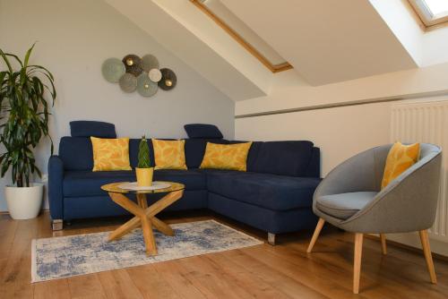 a blue couch and a chair in a living room at Eliza 1 Birdland Golf Apartman in Bük