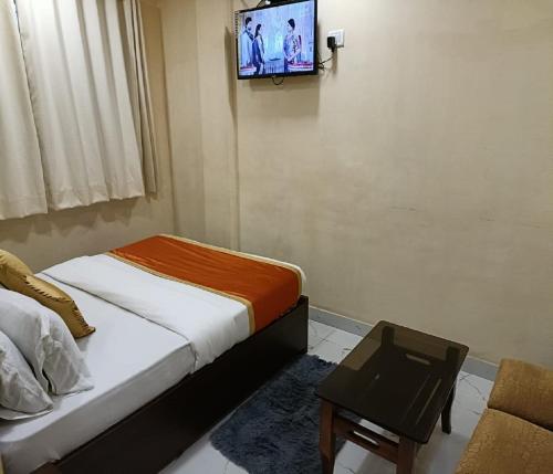 a bedroom with a bed and a tv on the wall at Hotel Royal Residency in Navi Mumbai