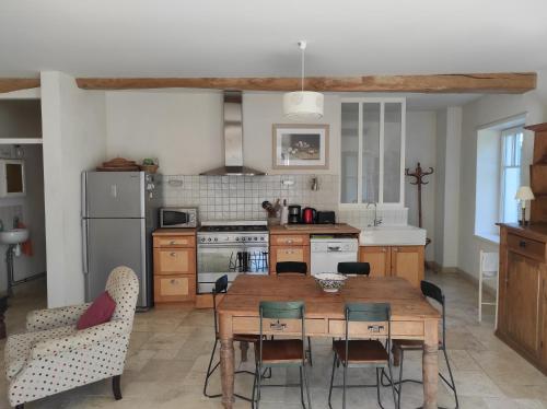eine Küche mit einem Holztisch und Stühlen in der Unterkunft Le Fournil des Jardins d'Ayaël in Ozenay