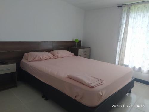 a bedroom with a bed with white sheets and pink pillows at La cabaña M in Pereira