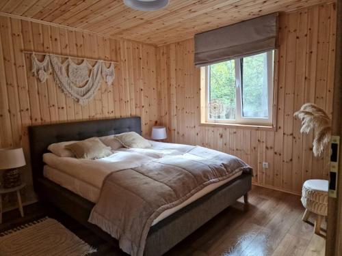 a bedroom with a large bed in a wooden wall at Svečių namai Banga in Paplatelė
