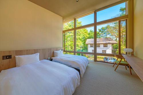 two beds in a room with a large window at Ren chalet in Hakuba
