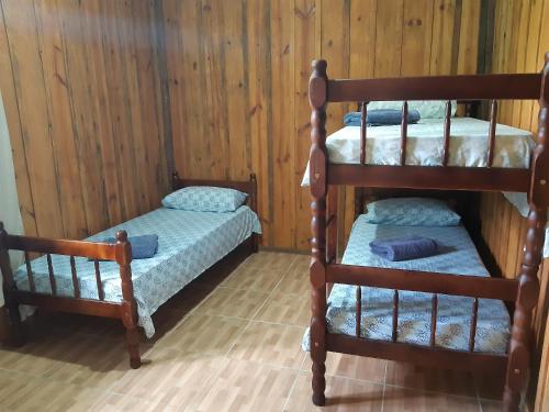 2 literas en una habitación con paredes de madera en Pousada Serra Verde Ecolodges, en Morretes