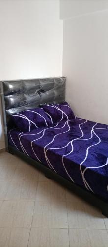 Bett in einem Zimmer mit lila Daunendecke in der Unterkunft Aswa9 salam in Kenitra