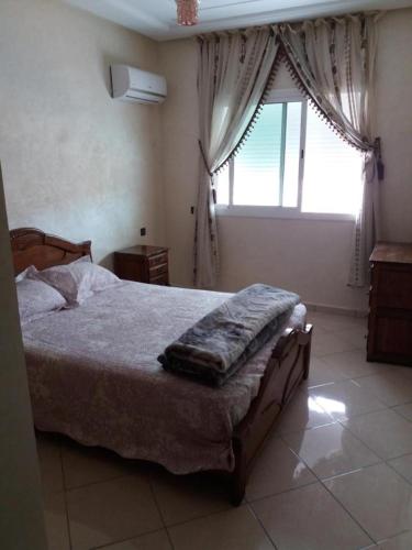 ein Schlafzimmer mit einem Bett und einem großen Fenster in der Unterkunft Aswa9 salam in Kenitra