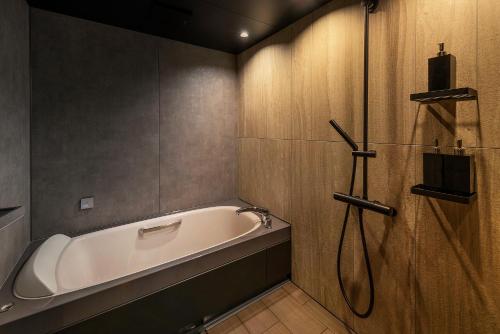 een badkamer met een bad en een douche bij Ren chalet in Hakuba