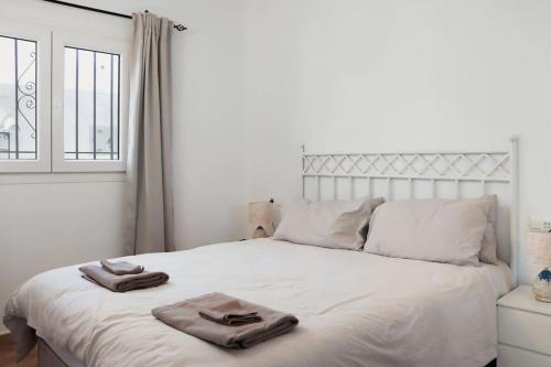 1 dormitorio con 1 cama blanca y 2 toallas en Capistrano Village, 1 bedroom, en Nerja