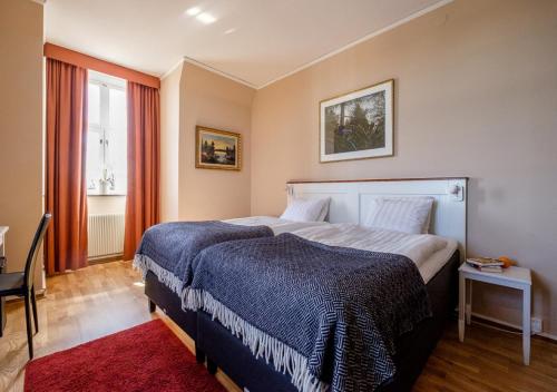 a bedroom with a large bed with a blue blanket at Eksjö Stadshotell in Eksjö