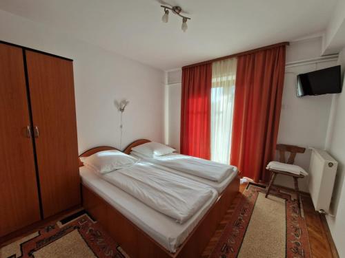 1 dormitorio con cama y cortina roja en Pensiunea Irina, en Vama