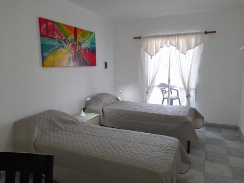 een slaapkamer met 2 bedden en een raam met een stoel bij CELESTINA in Cordoba