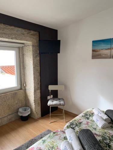 a bedroom with a bed and a chair next to a window at Hostel Eleven in Esposende