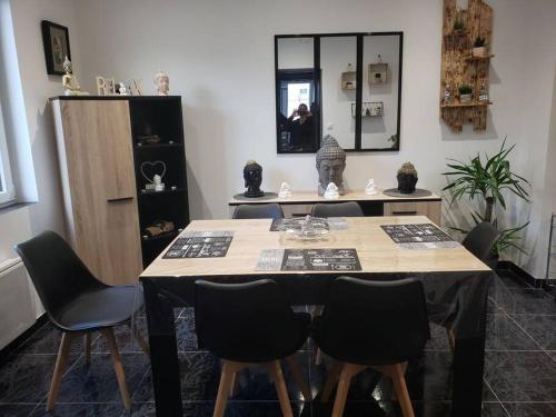 mesa de comedor con sillas negras y espejo en Maison chez fredo, en Calais