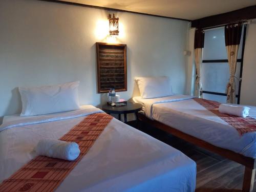 ein Hotelzimmer mit 2 Betten und einem Tisch in der Unterkunft Baanfai Guesthouse Chiangkhong in Chiang Khong
