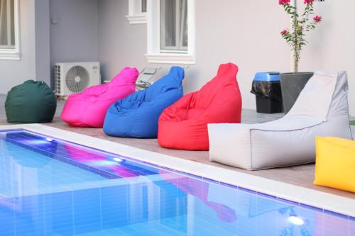 four colorful bean chairs sitting next to a swimming pool at Vila ELARAD in Vlorë