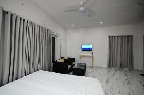 a bedroom with a bed and a chair and a television at RK MOUNT ORCHID coorg in Madikeri