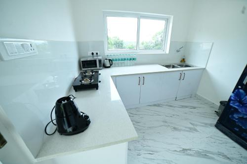 a white kitchen with a sink and a microwave at RK MOUNT ORCHID coorg in Madikeri