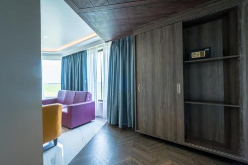 a living room with a purple chair and a window at Hotel Parkelite in Gannavaram