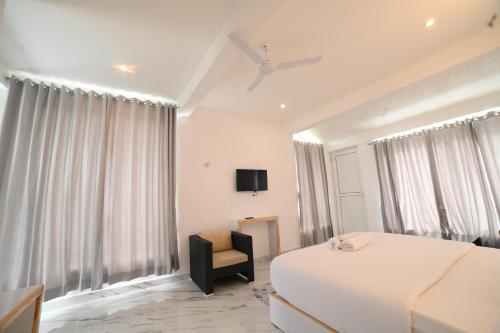 a bedroom with a bed and a chair and a tv at RK MOUNT ORCHID coorg in Madikeri