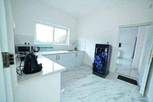 a white kitchen with a white counter and a refrigerator at RK MOUNT ORCHID coorg in Madikeri