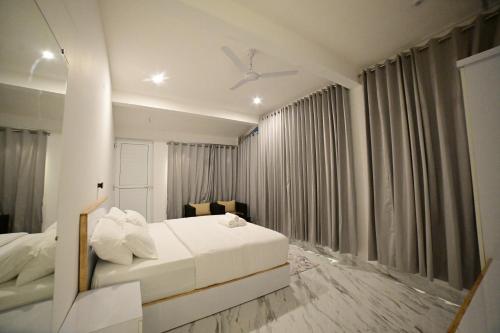 a bedroom with a white bed and a ceiling fan at RK MOUNT ORCHID coorg in Madikeri