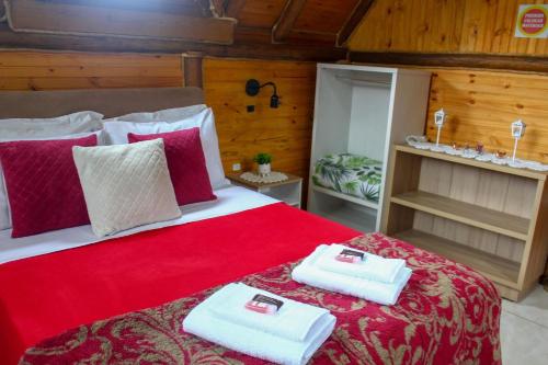 a bedroom with a red bed with towels on it at Chale com Wi-Fi e muito lazer em Bom Retiro SC in Bom Retiro