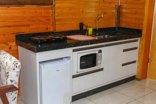 a kitchen counter with a sink and a microwave at Chale com Wi-Fi e muito lazer em Bom Retiro SC in Bom Retiro