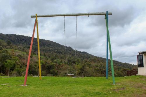a swing set in a field with a mountain at Chale com Wi-Fi e muito lazer em Bom Retiro SC in Bom Retiro