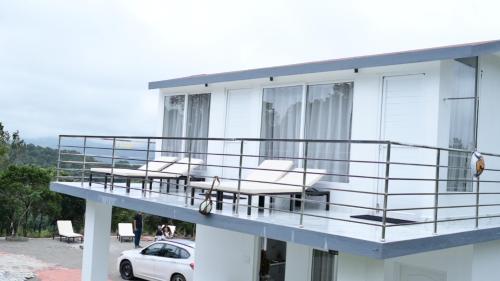 a balcony of a house with chairs and a car at RK MOUNT ORCHID coorg in Madikeri