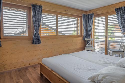 a bedroom with a bed and two windows at Laackerhof in Bettmeralp