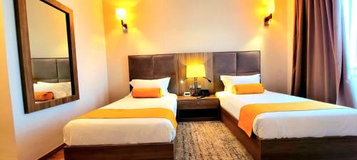 a hotel room with two beds and a mirror at TH BonRoyal Hotel in Addis Ababa