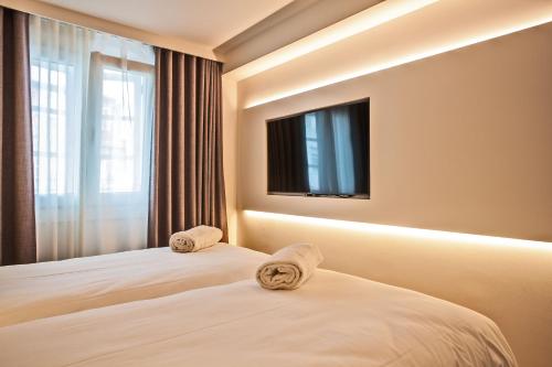 a bedroom with two beds with a television on the wall at Hotel Plaza Obradoiro by Bossh! Hotels in Santiago de Compostela