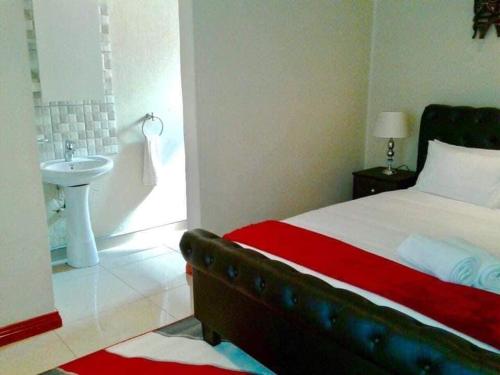 a bedroom with a bed and a bathroom with a sink at Lamamie guest house in Thohoyandou