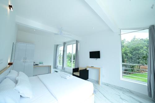 a white bedroom with a large bed and a window at RK MOUNT ORCHID coorg in Madikeri