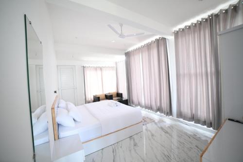 a white bedroom with a white bed and a mirror at RK MOUNT ORCHID coorg in Madikeri