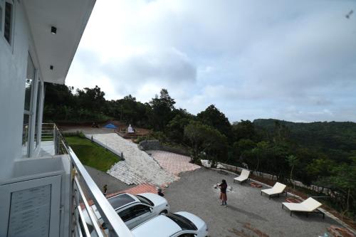 a woman standing on a balcony looking at a beach at RK MOUNT ORCHID coorg in Madikeri