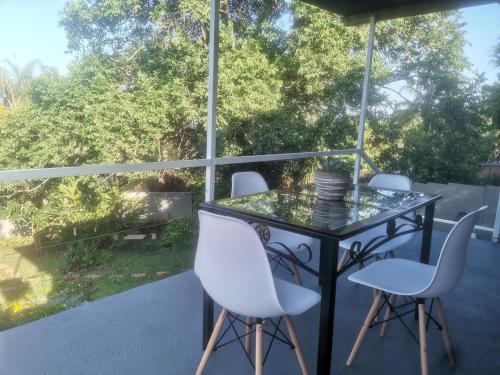 a glass table and white chairs on a patio at The Calm Views Holiday Home in Hazyview