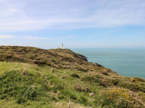 a lighthouse on top of a hill next to the ocean at Ty Canol in Mathry